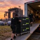 Crew rolling a stack of JM Boxes up a truck ramp at a festival at sunset